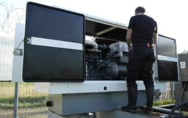 a generator with a man in front of it completing generator maintenance.